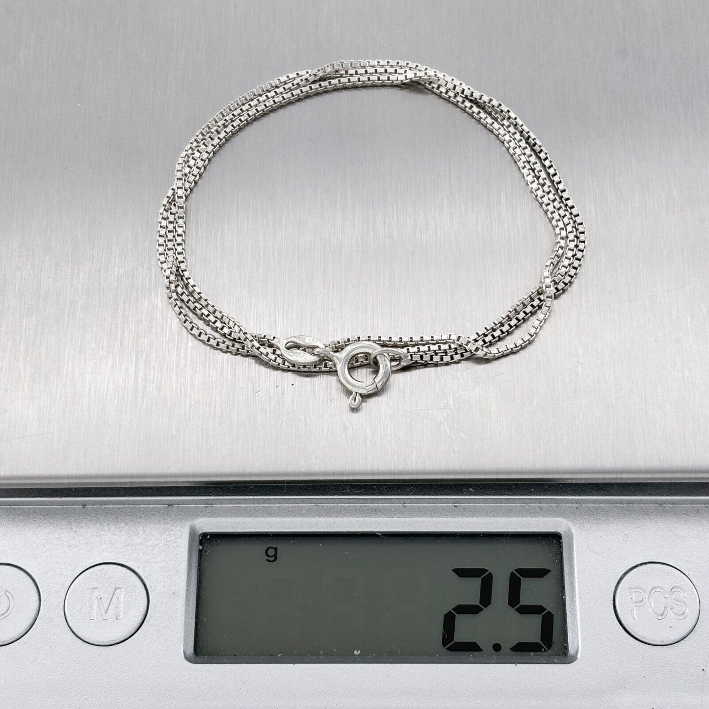Silver necklace on a digital scale displaying weight