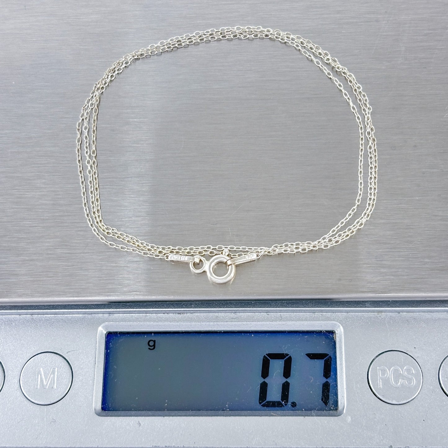 Silver necklace on a digital scale displaying weight