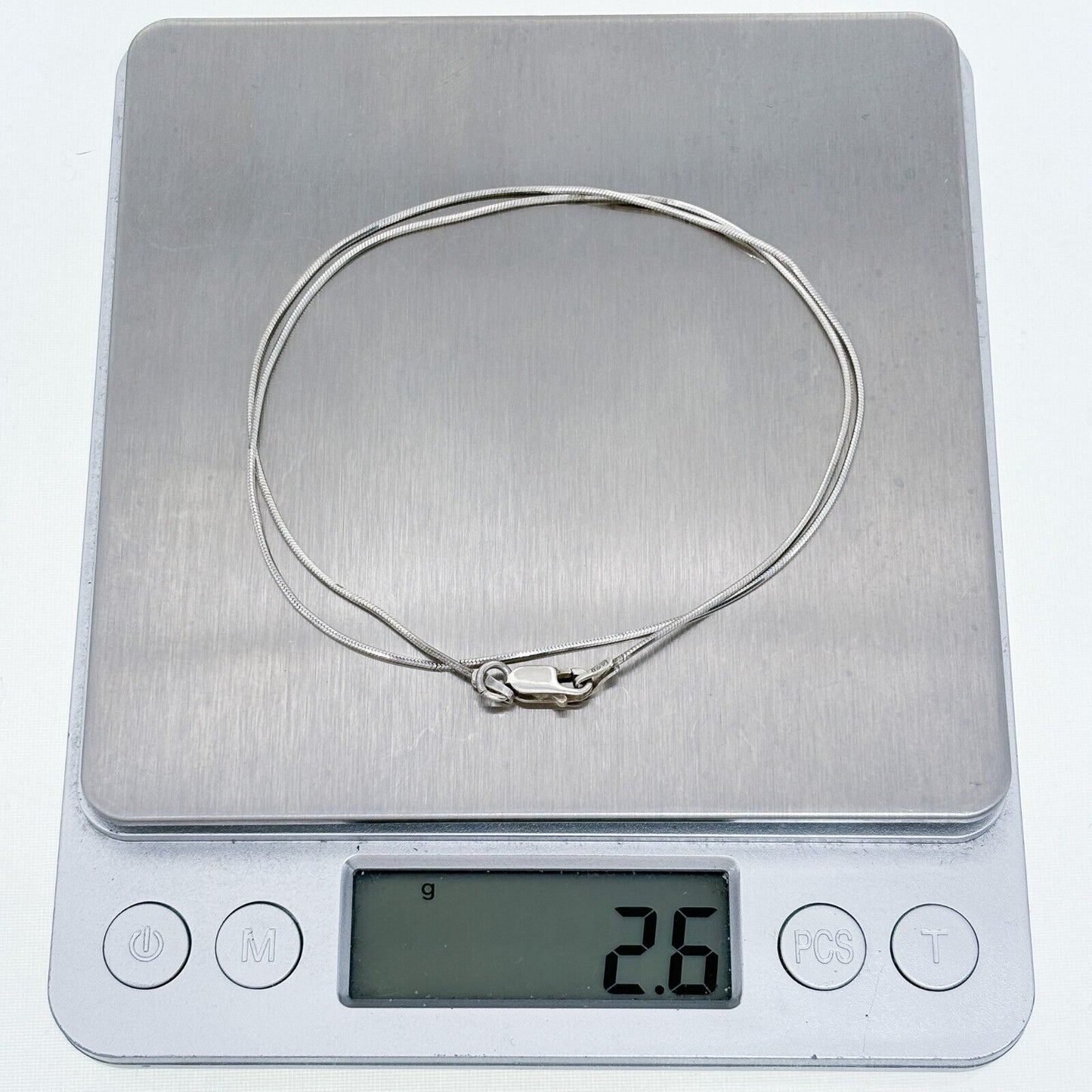 Silver necklace on a digital kitchen scale displaying weight