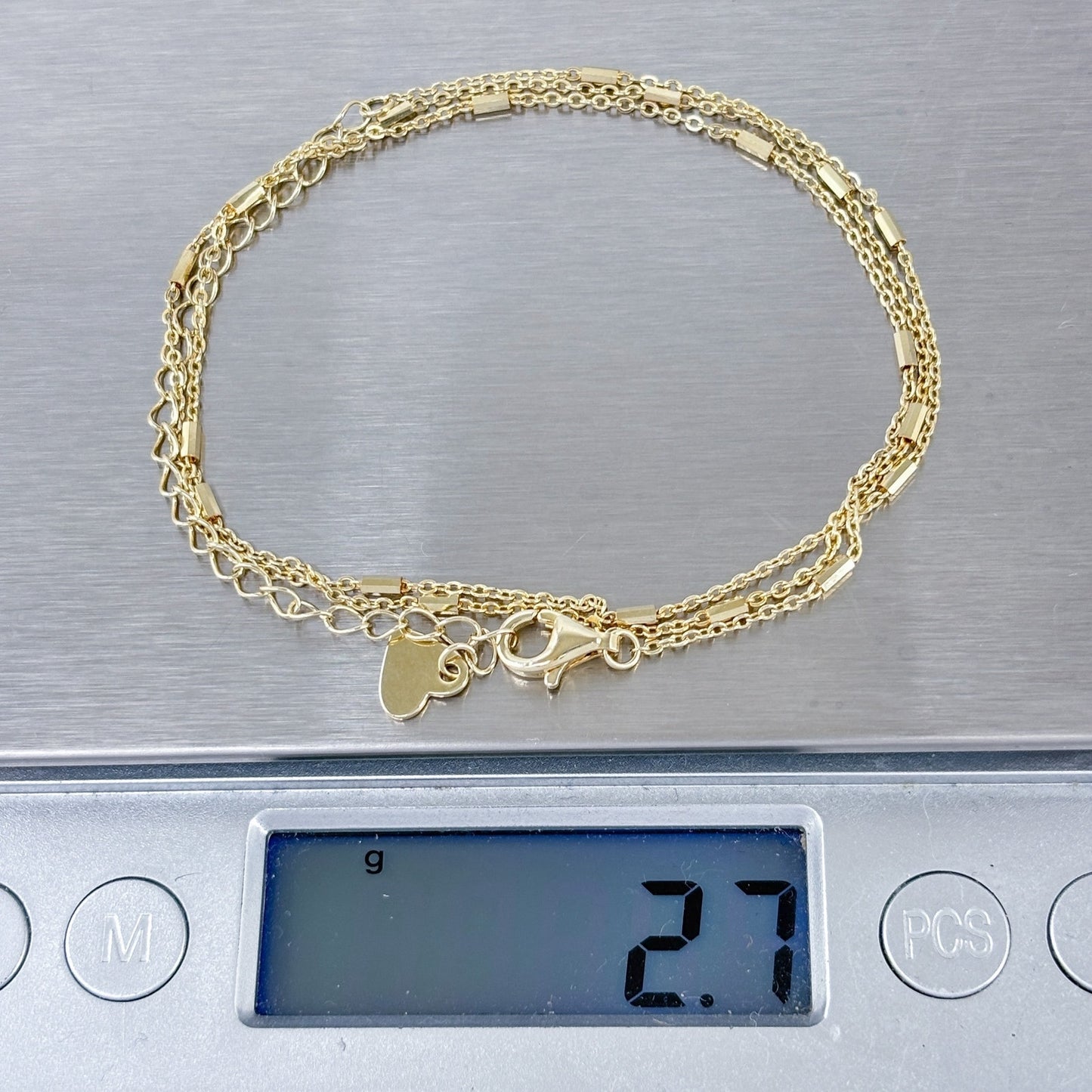 Gold necklace with heart charm on a digital scale displaying weight