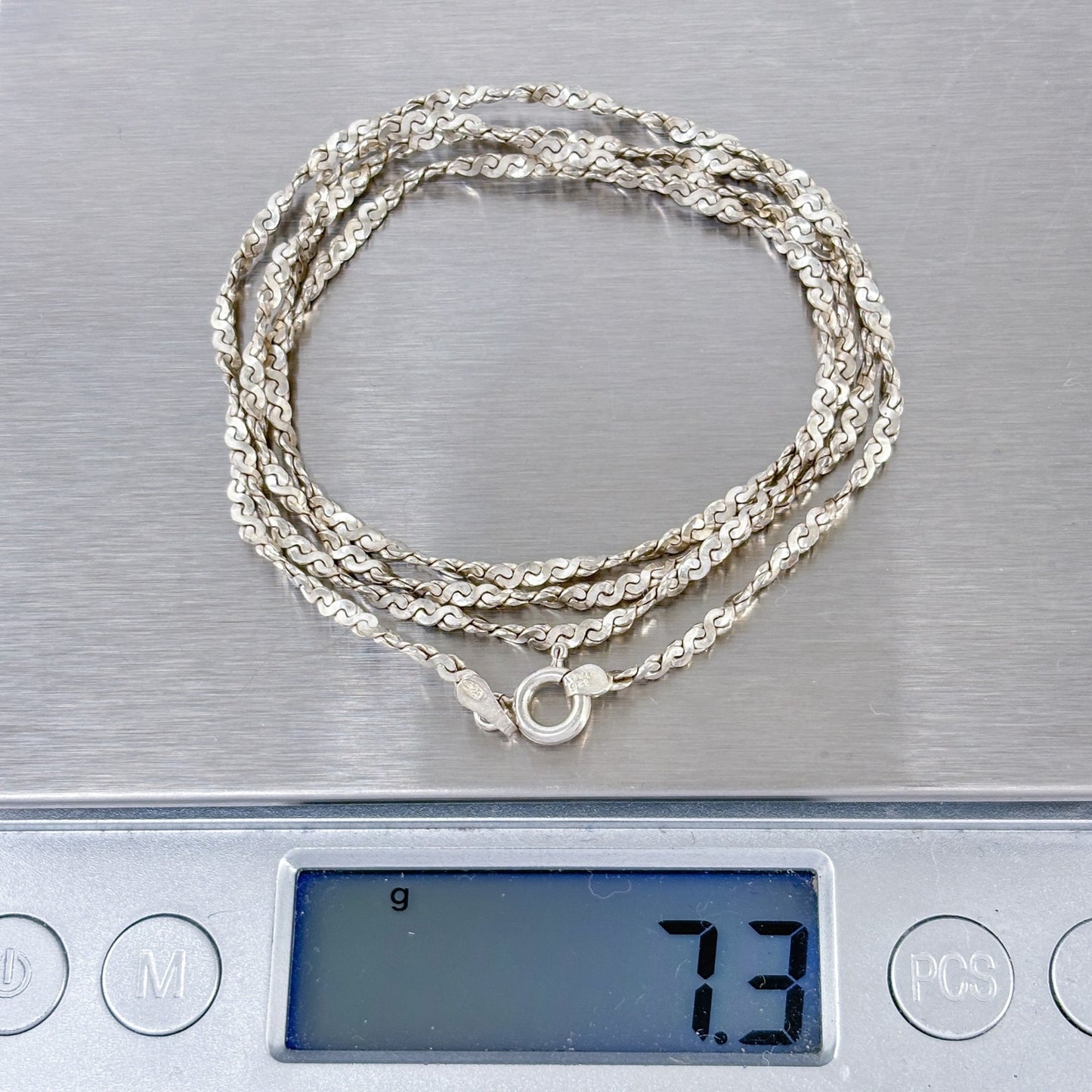 Silver necklace on a digital scale displaying weight