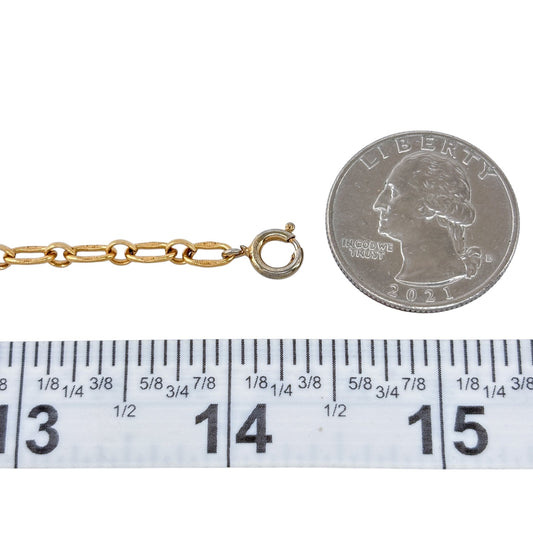 Gold chain with a clasp next to a quarter and ruler for size reference on a white background