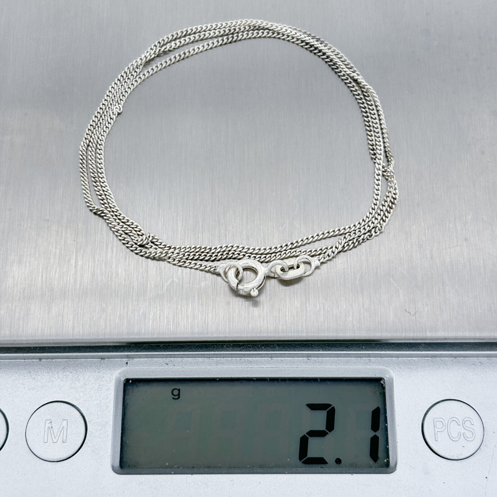 Silver chain on a digital scale displaying weight