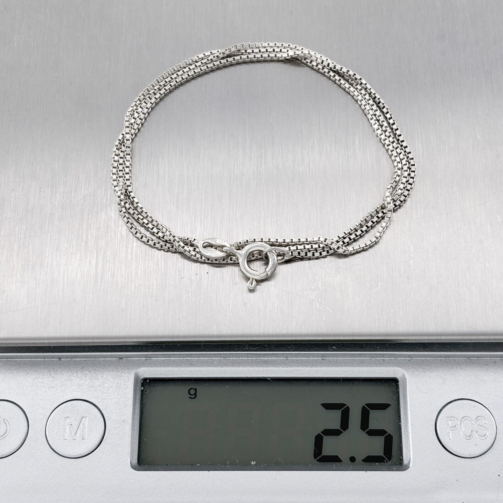 Silver necklace on a digital scale displaying weight