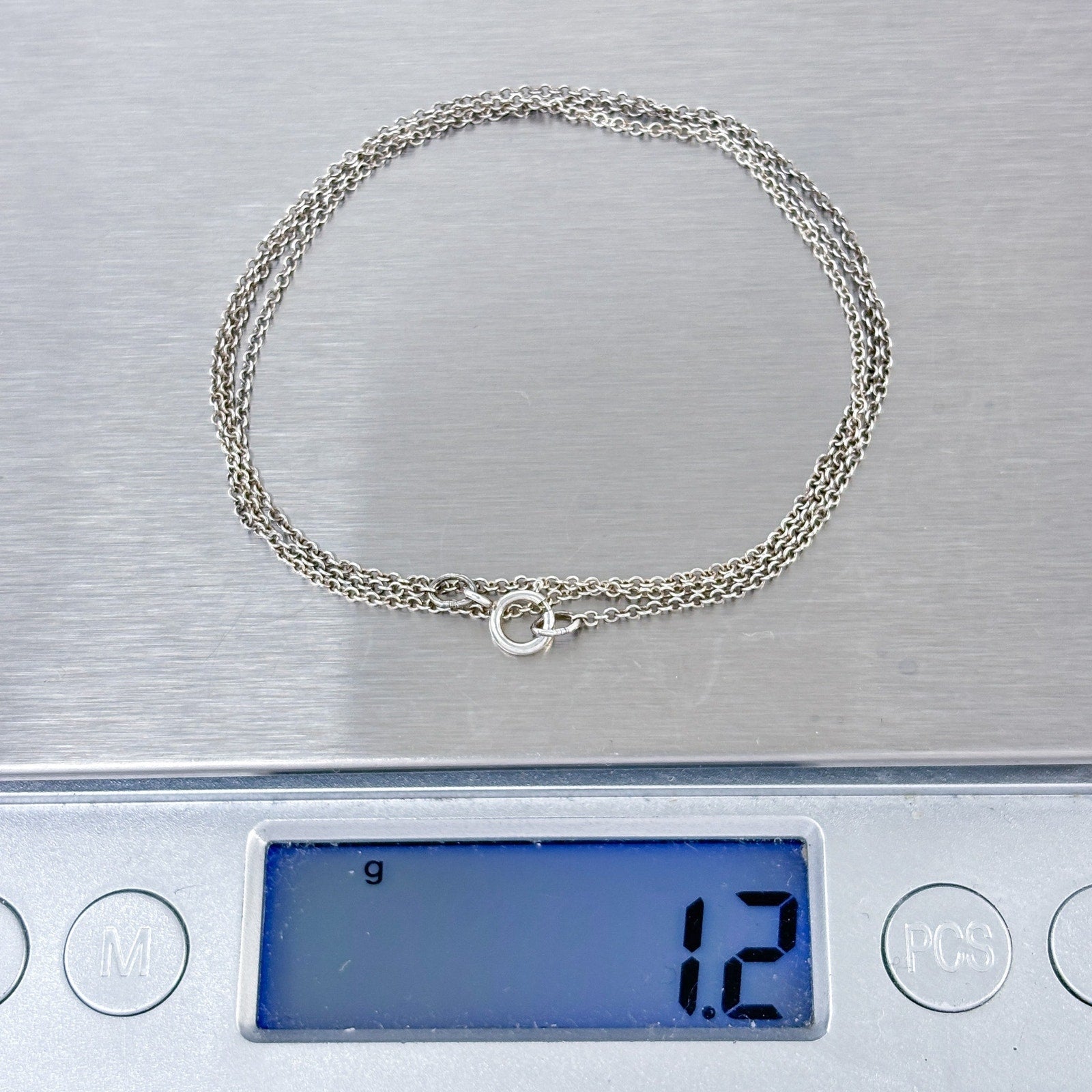 Silver bracelet on a digital scale displaying a weight of 12 grams.