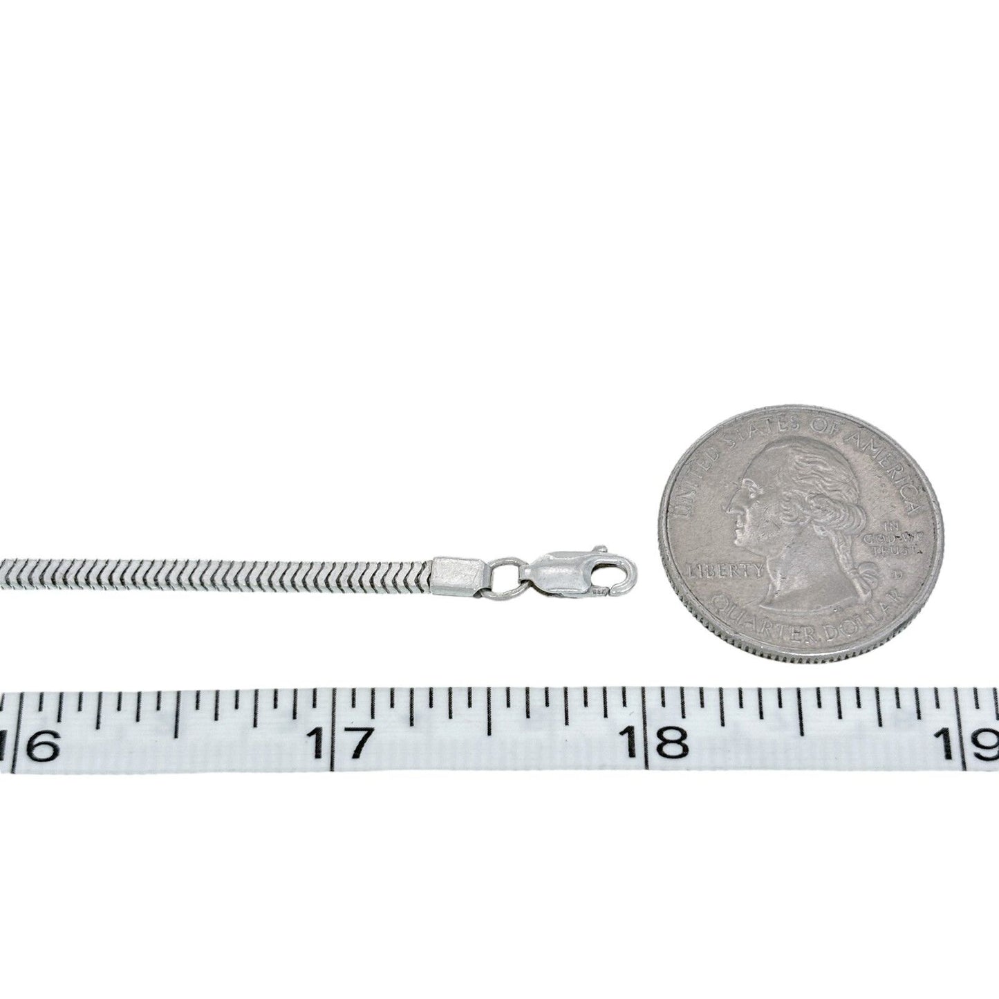 Silver chain necklace with a coin and measuring tape for scale on a white background