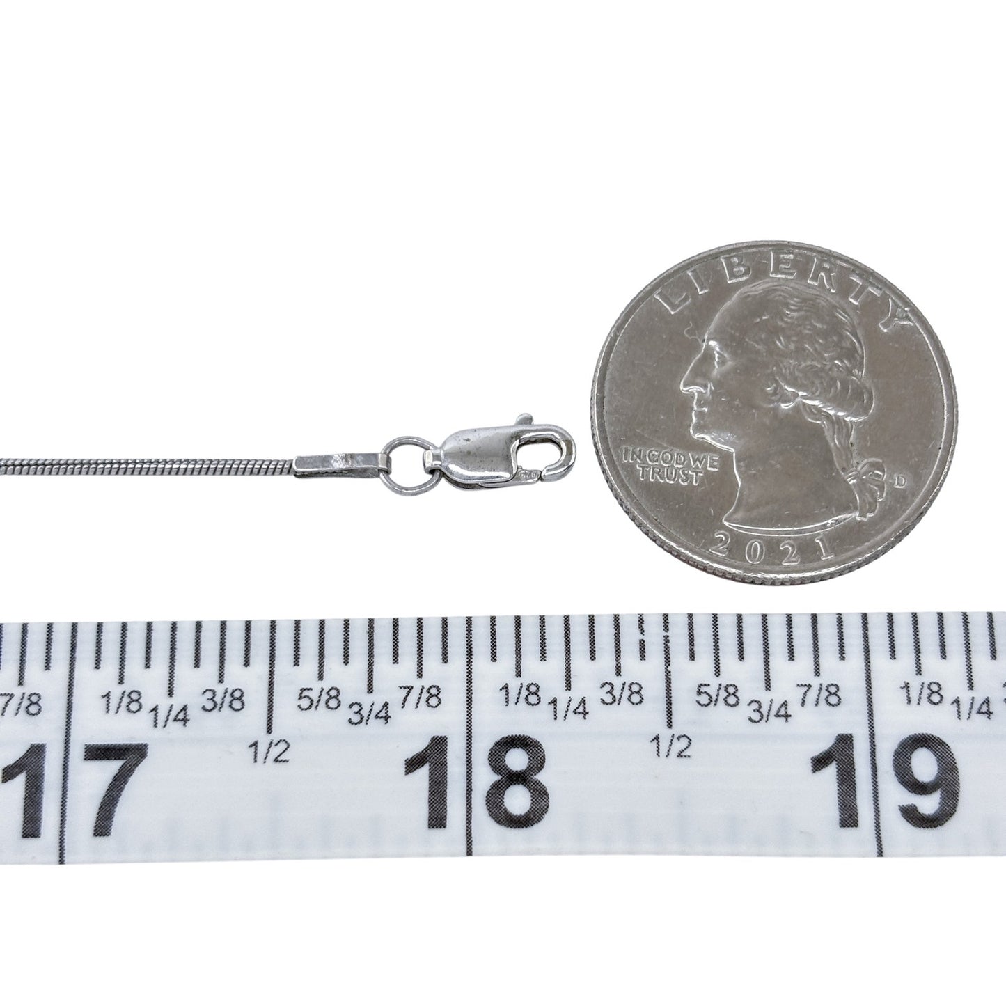 Silver chain with clasp next to a quarter and ruler for size reference on a white background