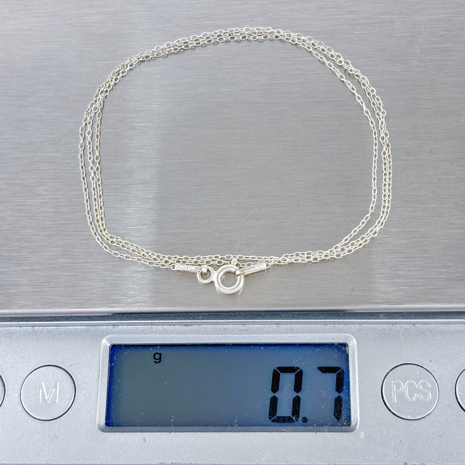 Silver necklace on a digital scale displaying weight
