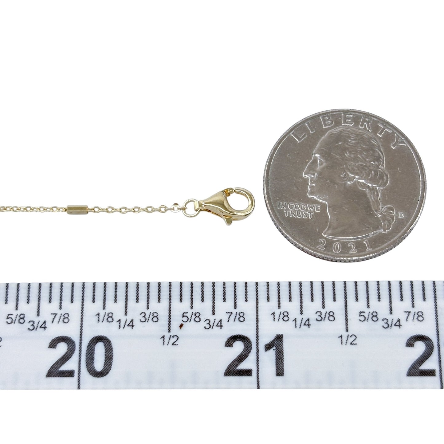 Gold necklace with clasp next to a quarter and ruler for measurement on a white background
