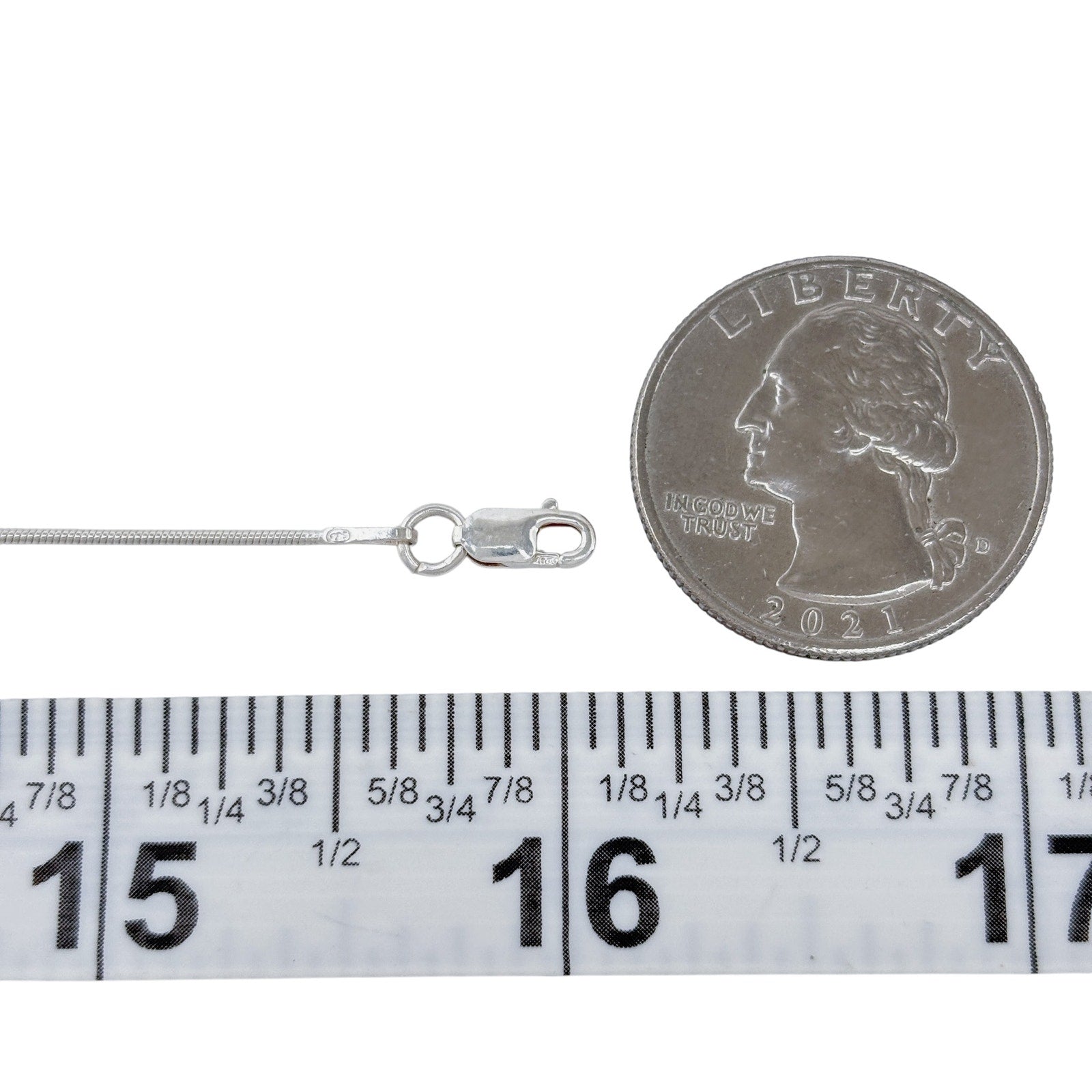 Silver necklace with a clasp next to a quarter and ruler for size reference on a white background