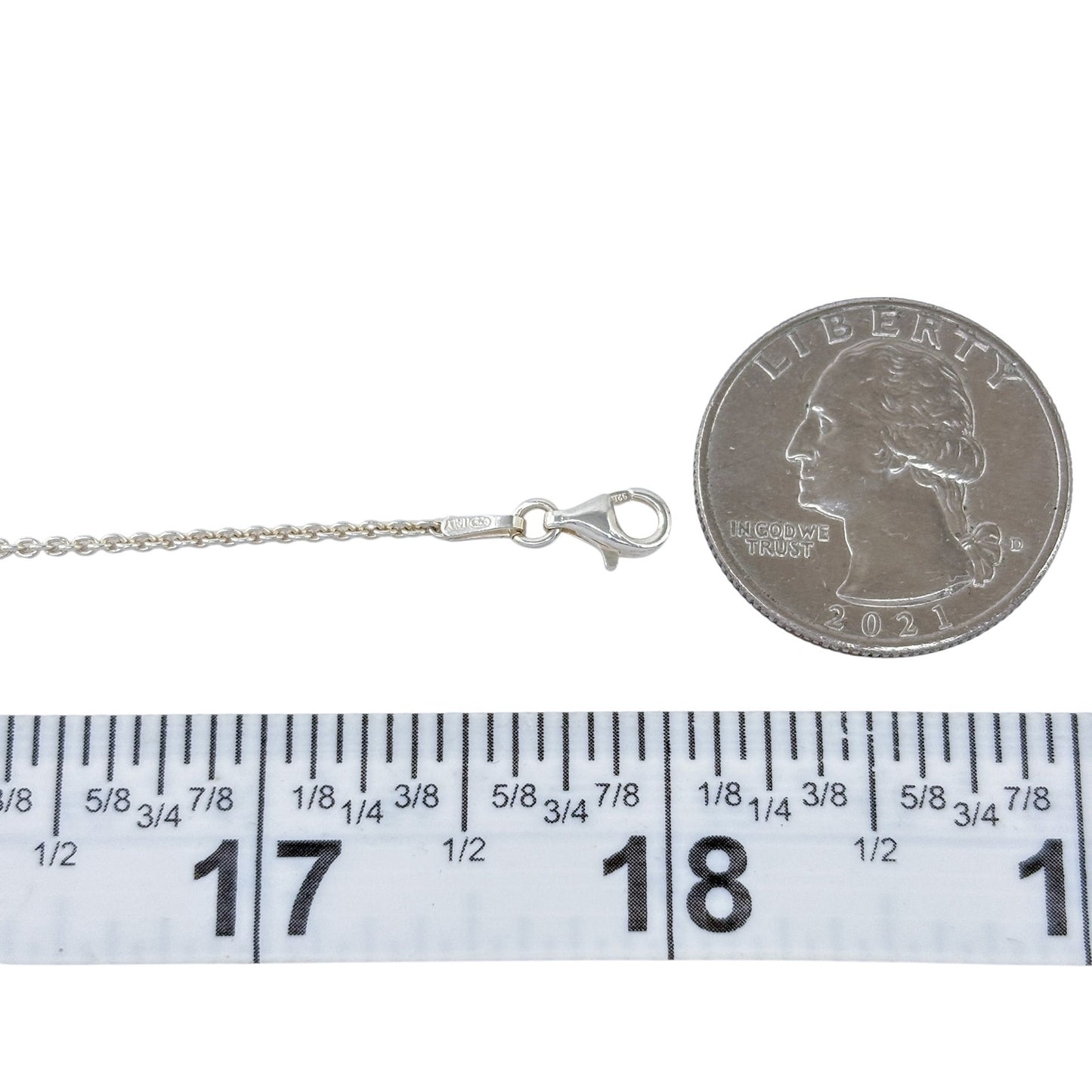 Silver necklace with clasp next to a quarter and ruler for size reference on a white background