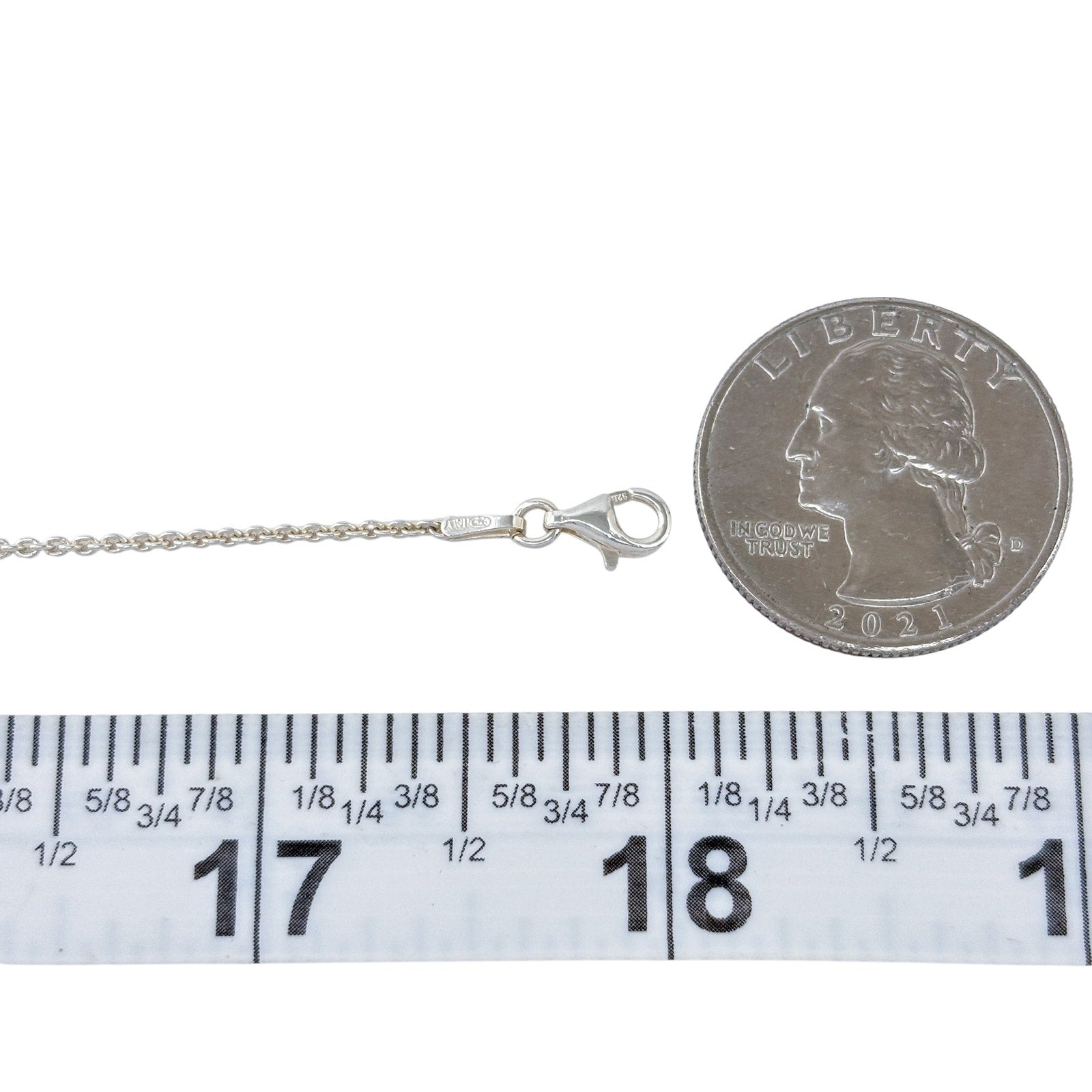 Silver necklace with clasp next to a quarter and ruler for size reference on a white background