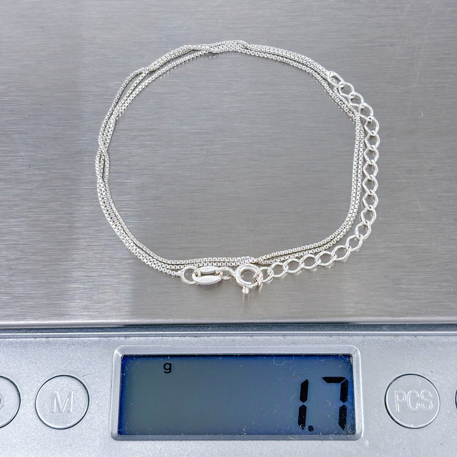 Silver chain bracelet on a digital scale displaying weight