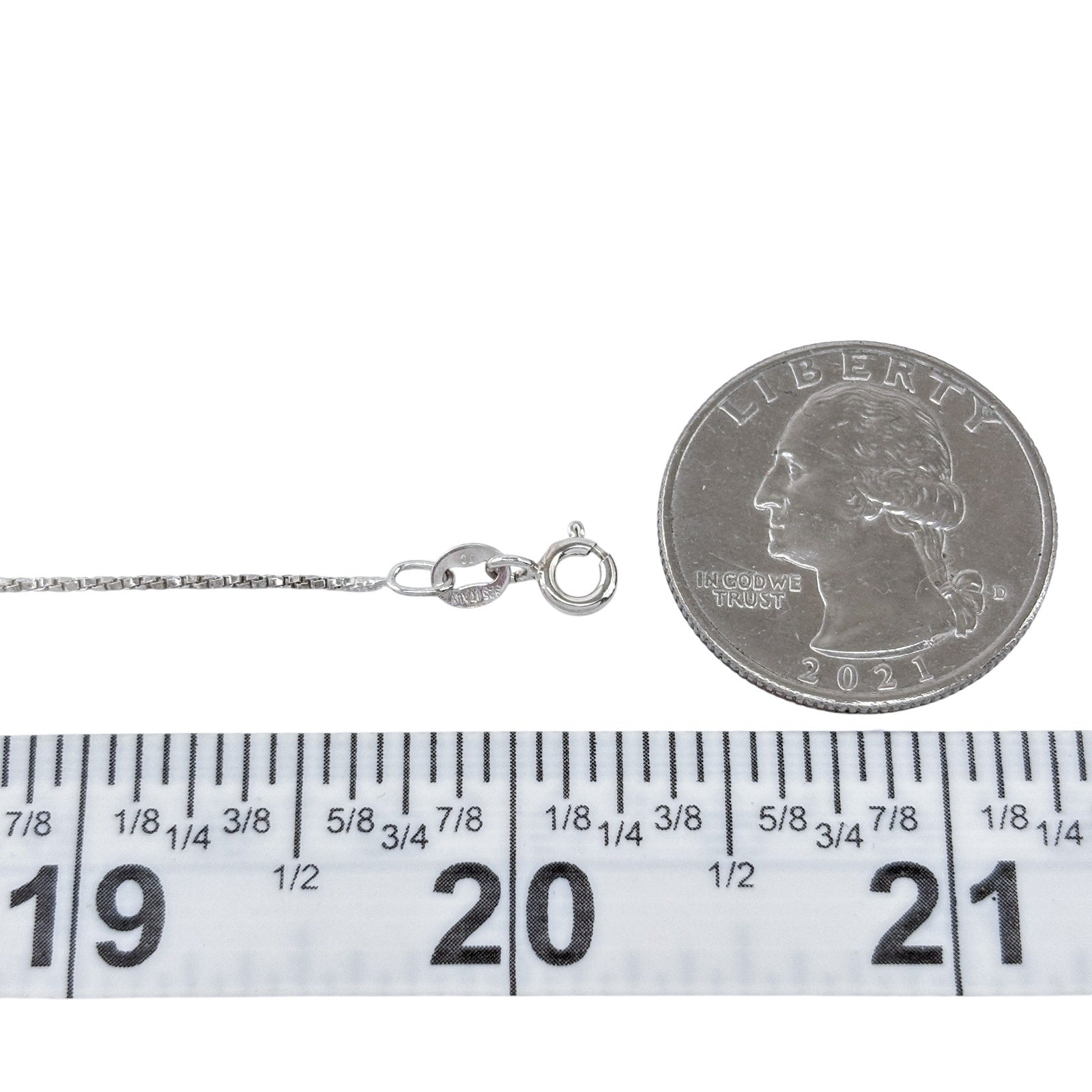 Silver necklace with a clasp next to a quarter and ruler for size reference on a white background