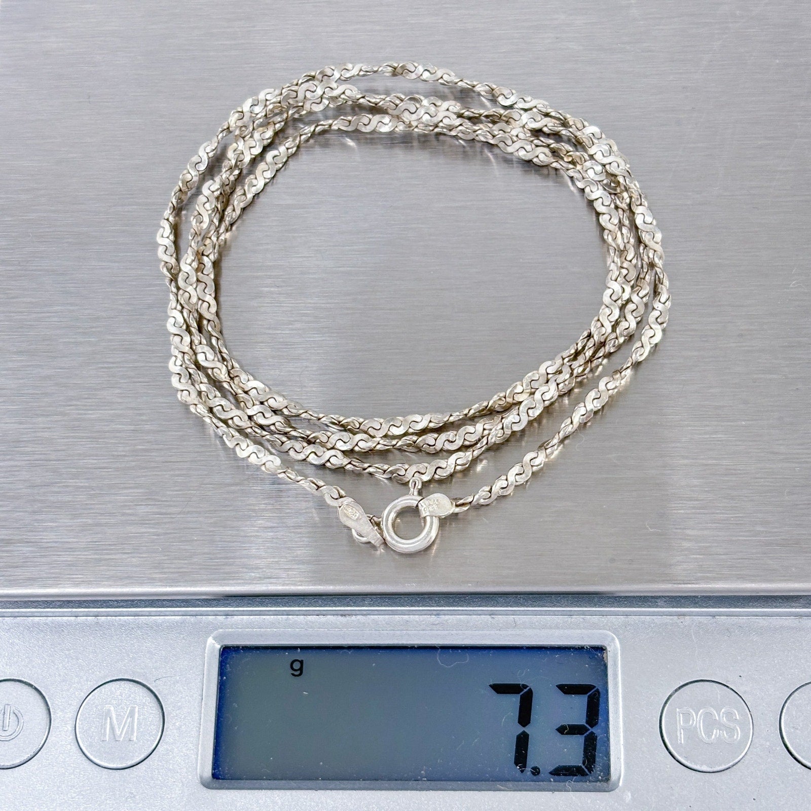 Silver necklace on a digital scale displaying weight