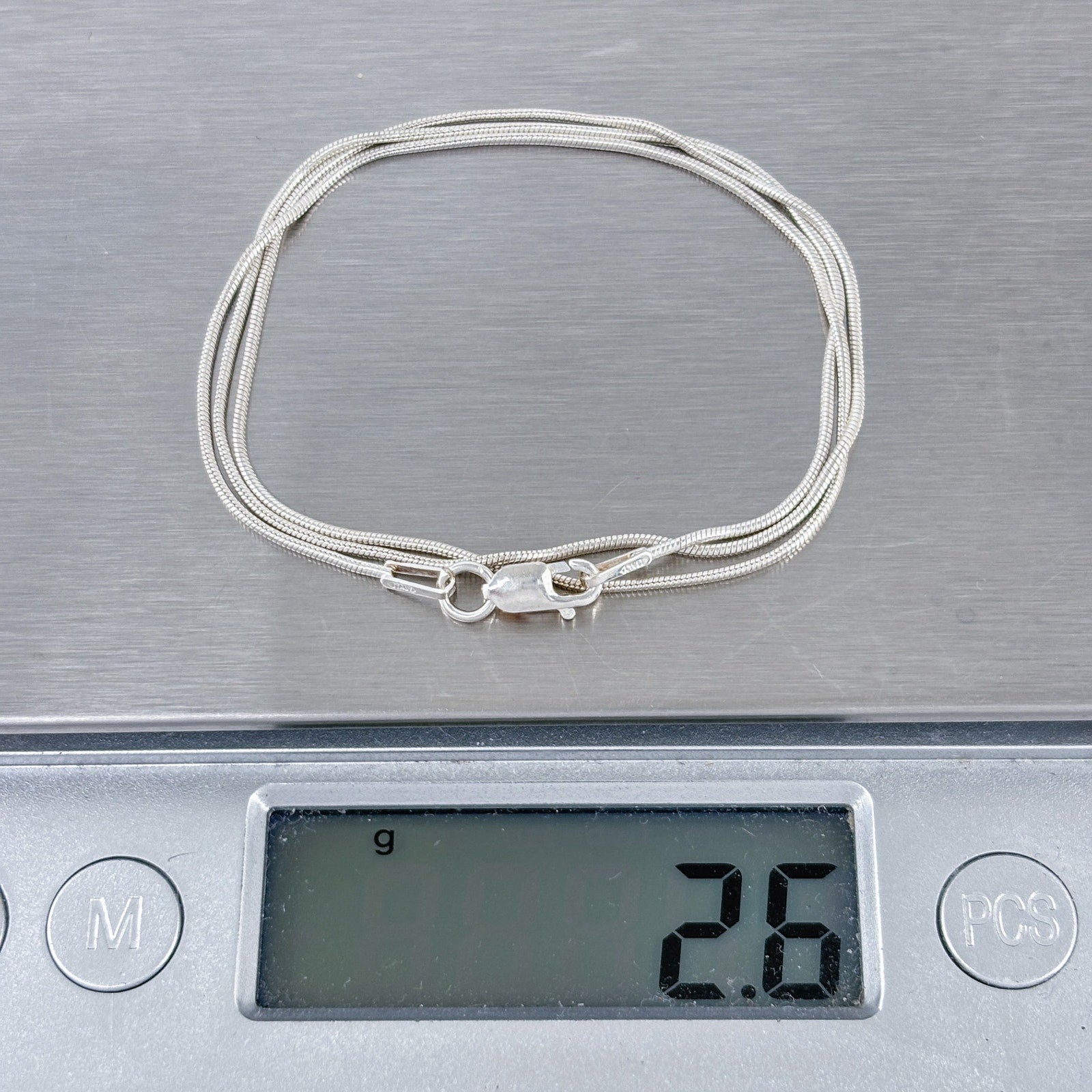 Silver bracelet on a digital scale displaying weight