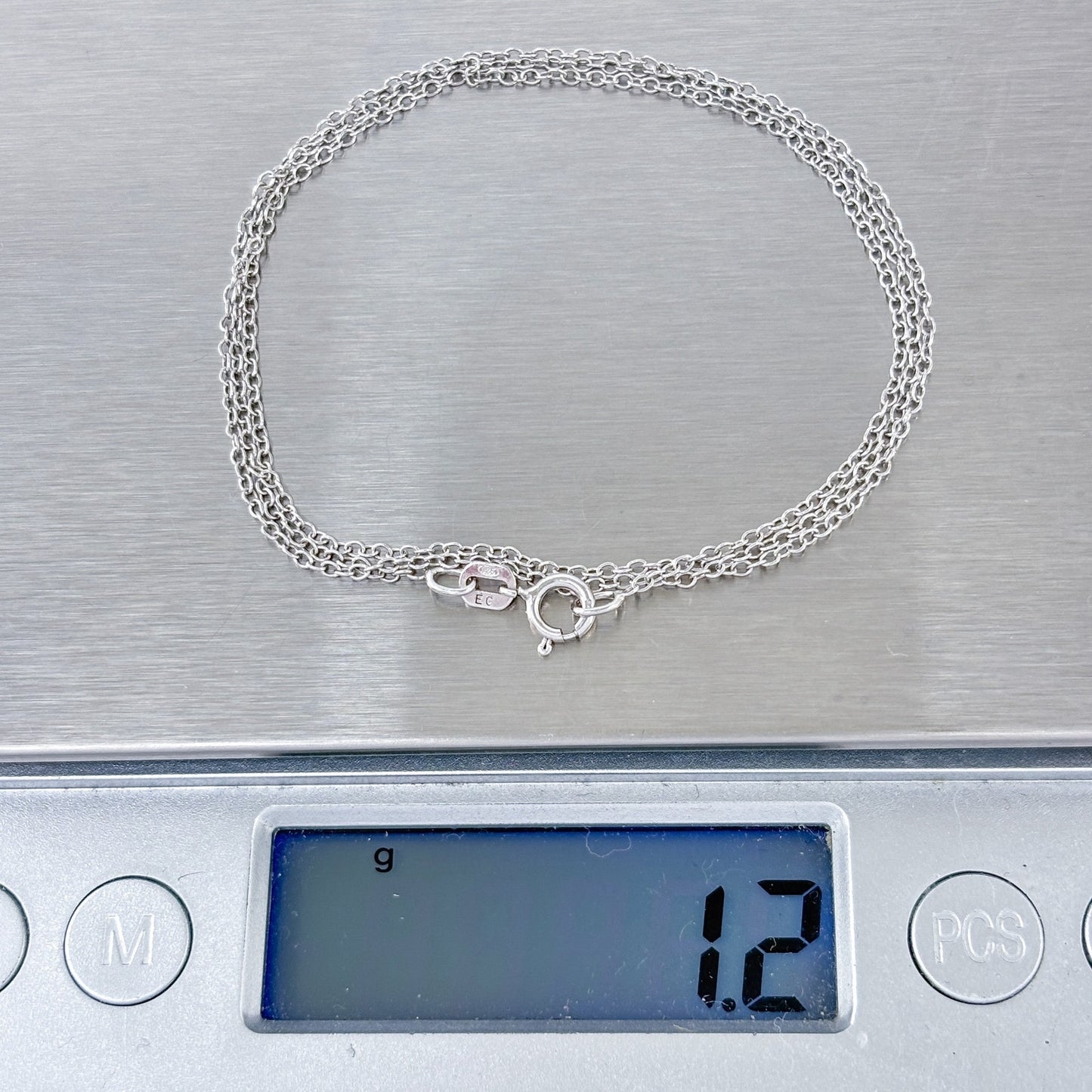 Silver necklace on a digital scale displaying a weight of 1.2 grams.