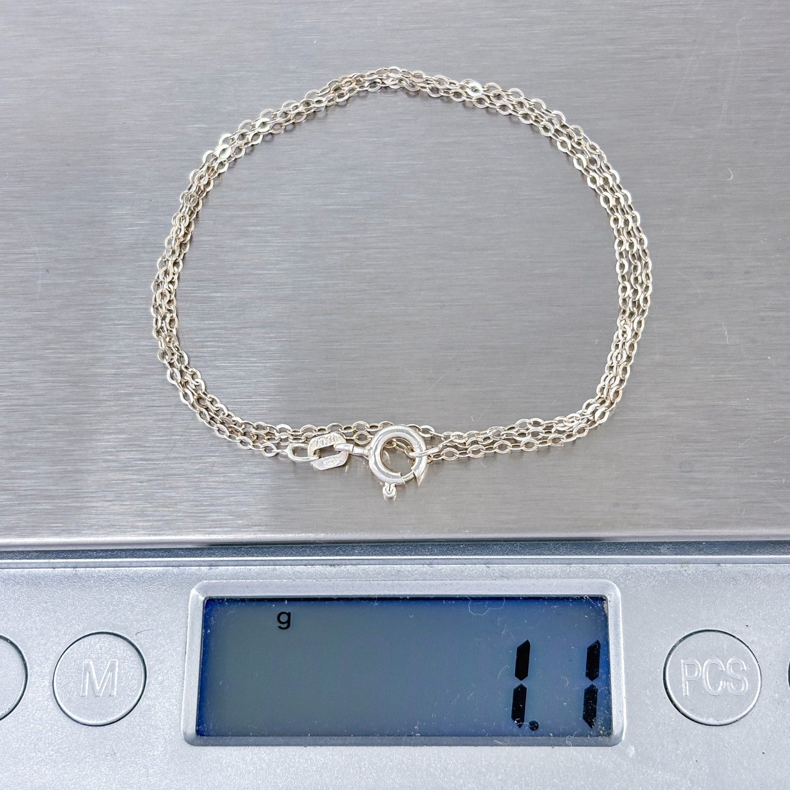 Silver necklace on a digital scale displaying a weight of 1.1 grams.