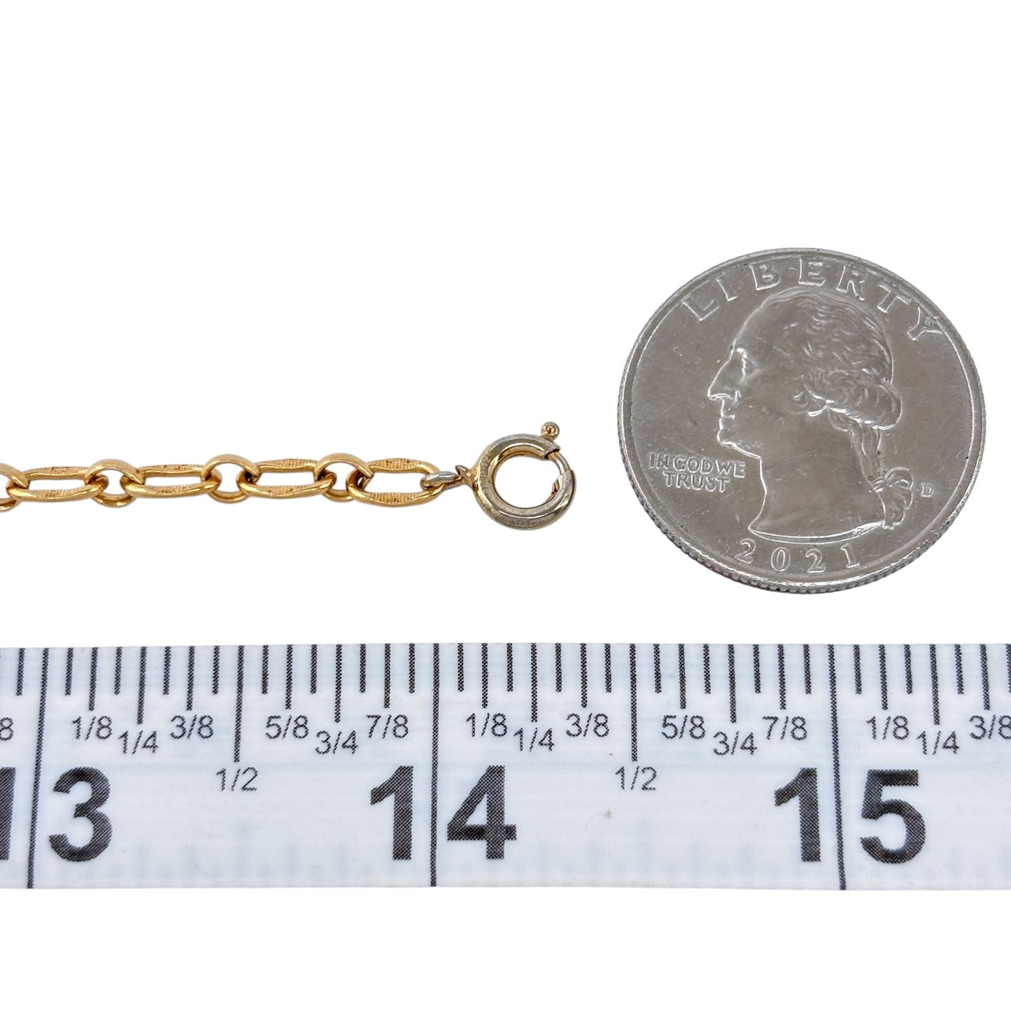 Gold chain with a clasp next to a quarter and ruler for size reference on a white background