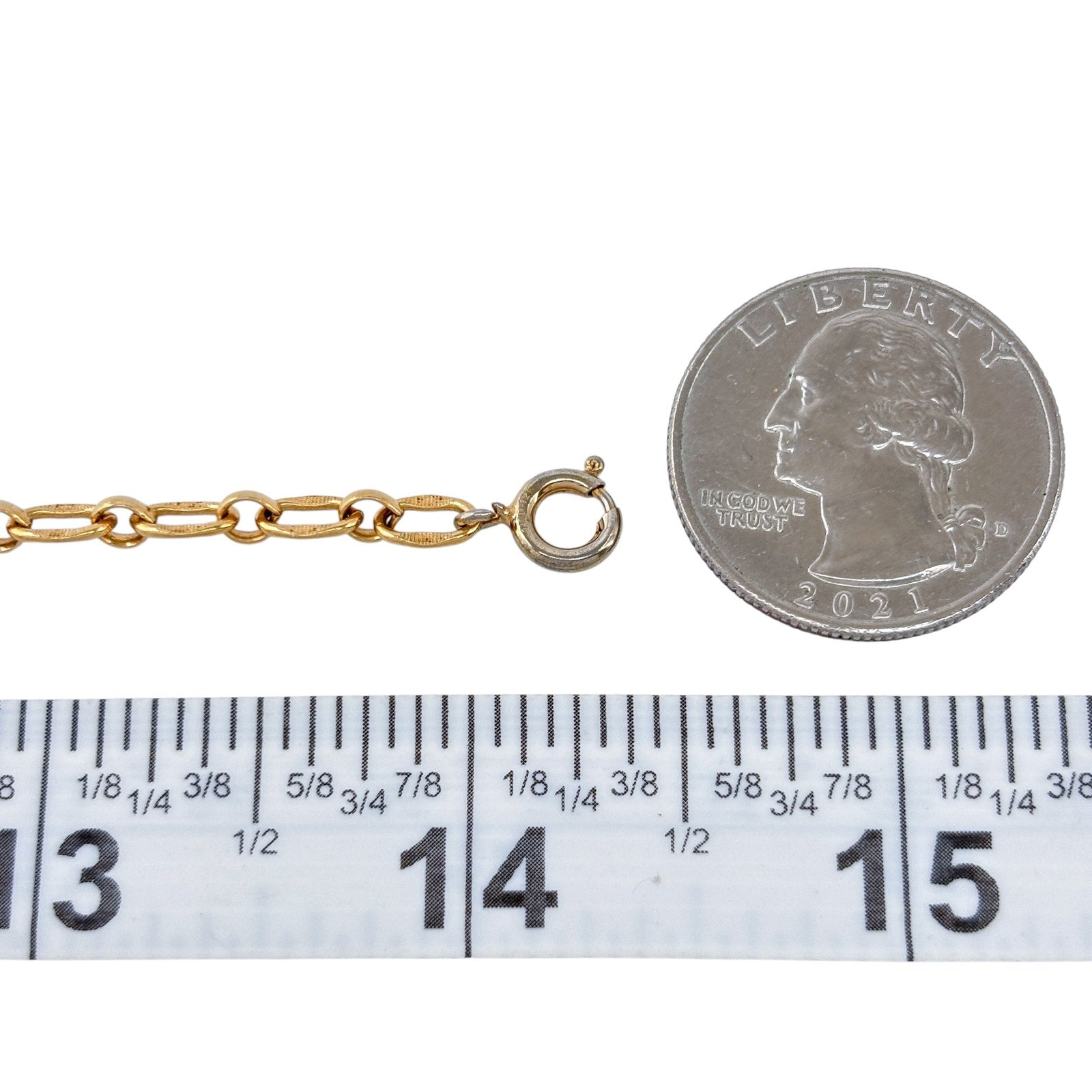 Gold chain with a clasp next to a quarter and ruler for size reference on a white background
