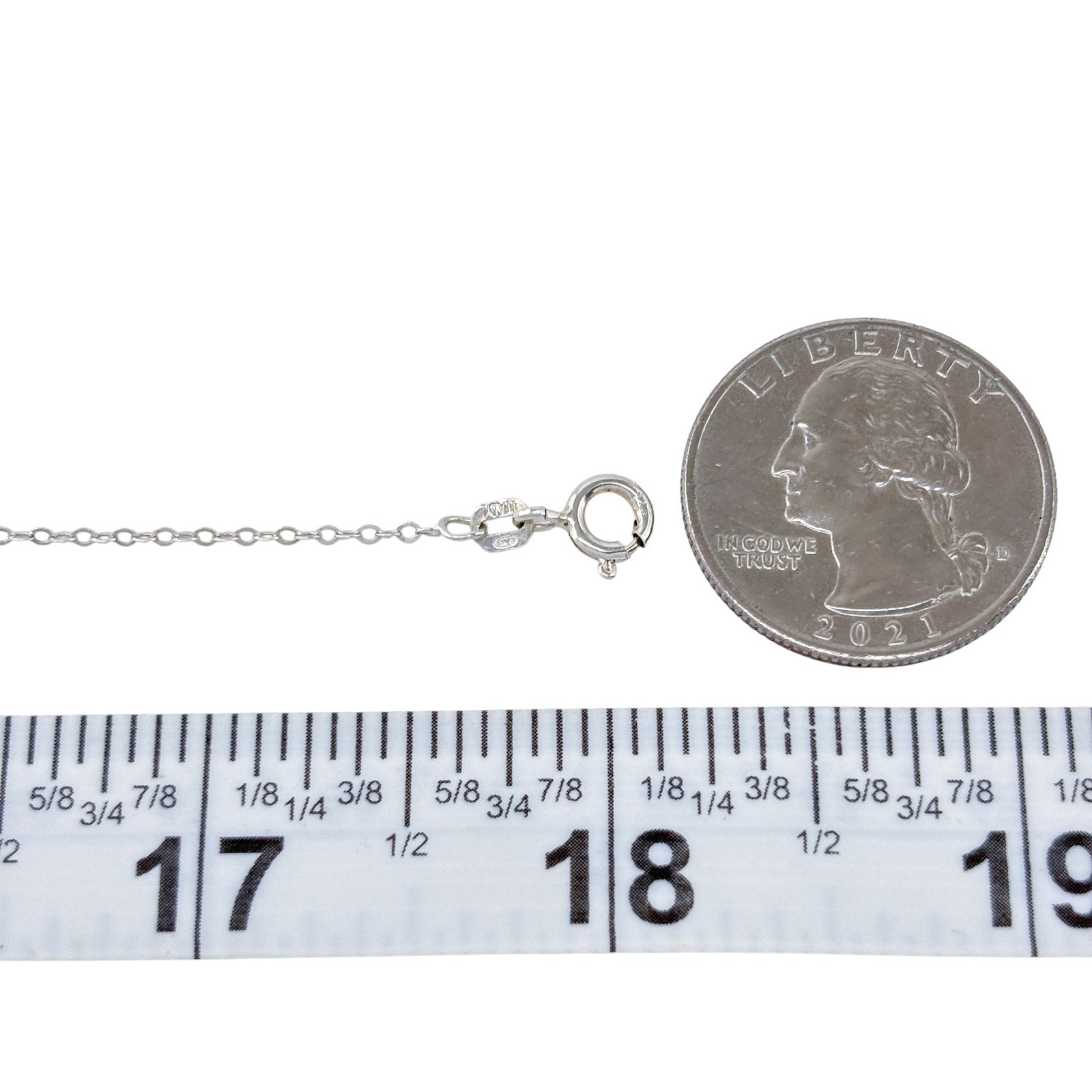 Silver necklace with clasp next to a quarter and ruler for size reference on a white background