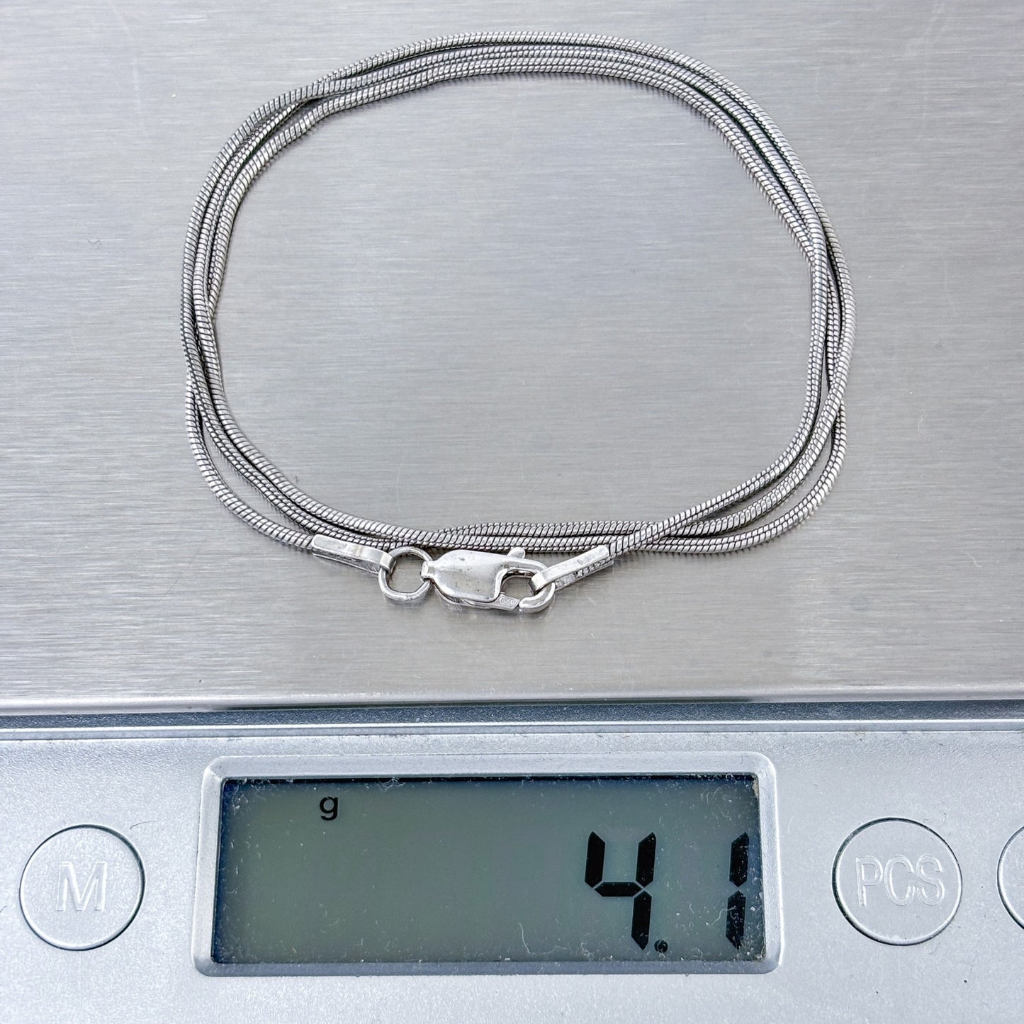 Silver snake chain necklace on a digital scale displaying weight