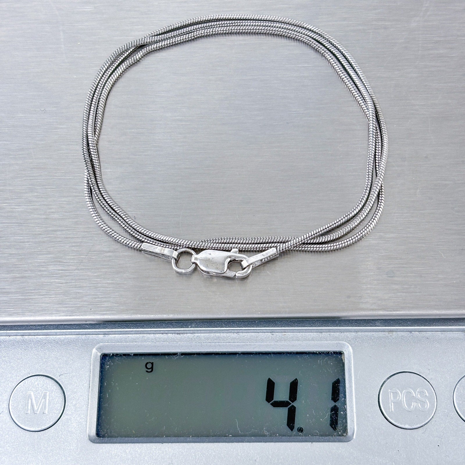 Silver snake chain necklace on a digital scale displaying weight