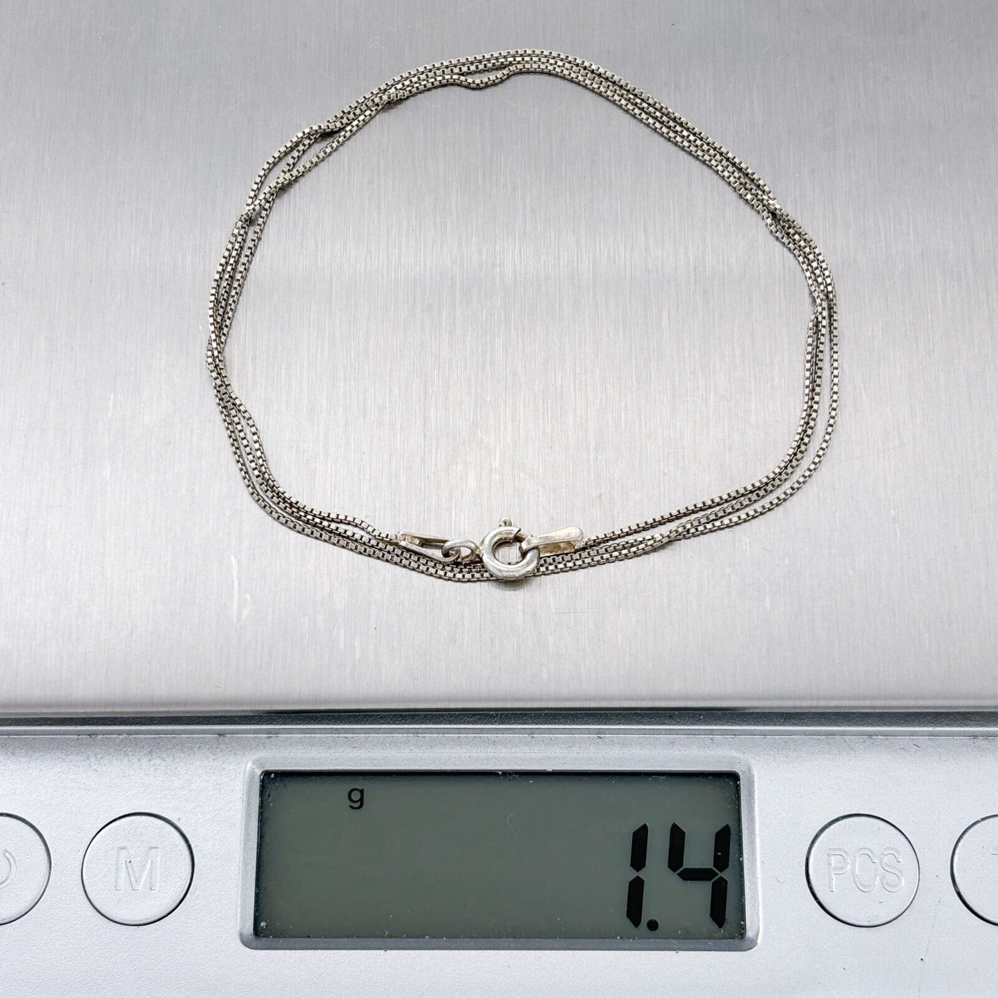 Silver chain on a digital scale displaying weight