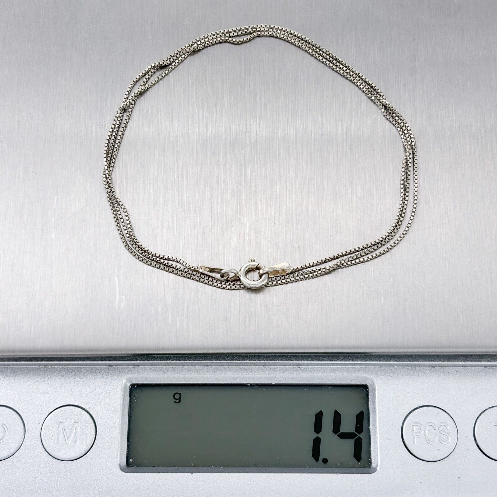 Silver chain on a digital scale displaying weight